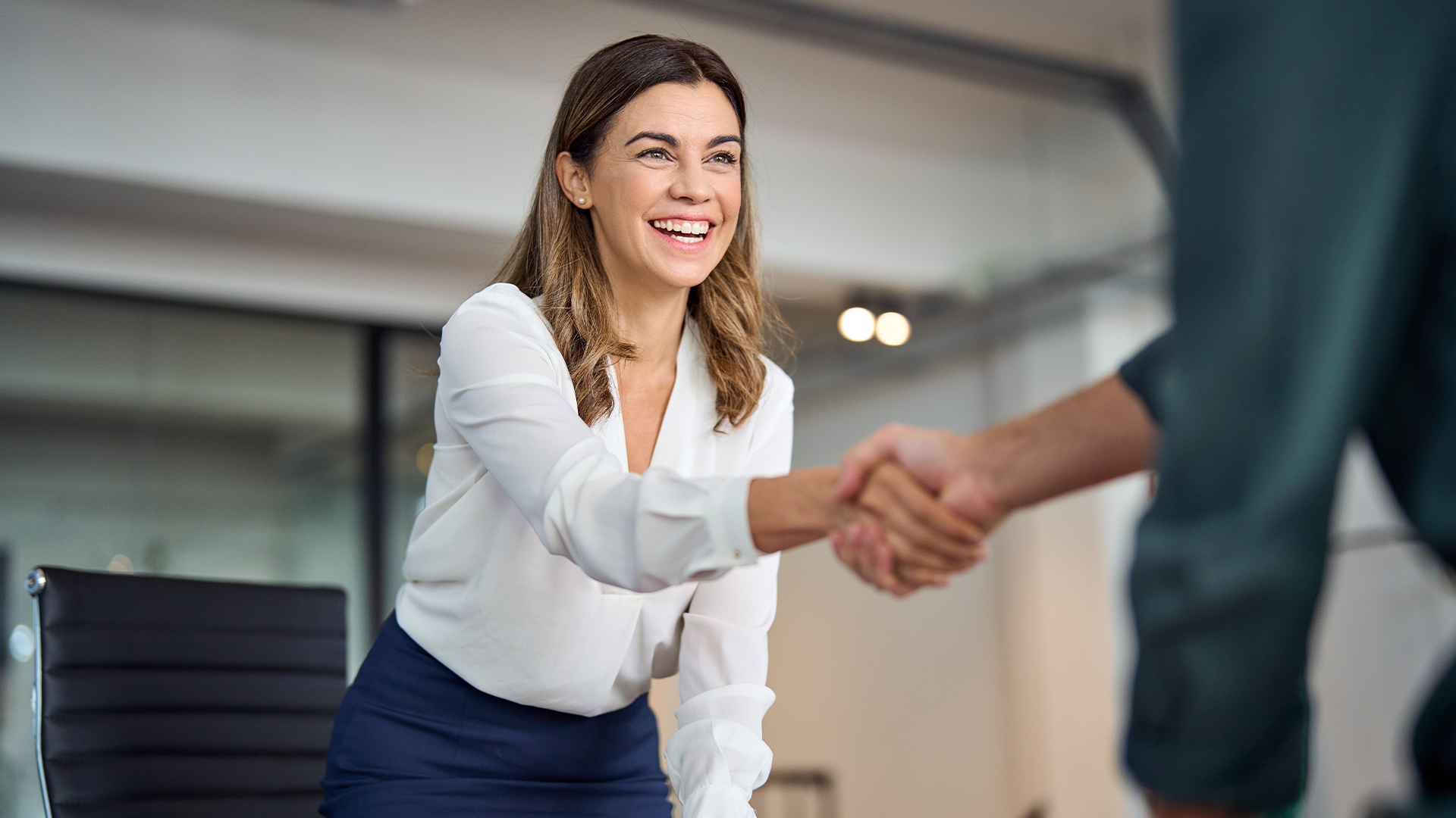 A women shaking hands with someone not in frame reflecting a client and accountant meeting.